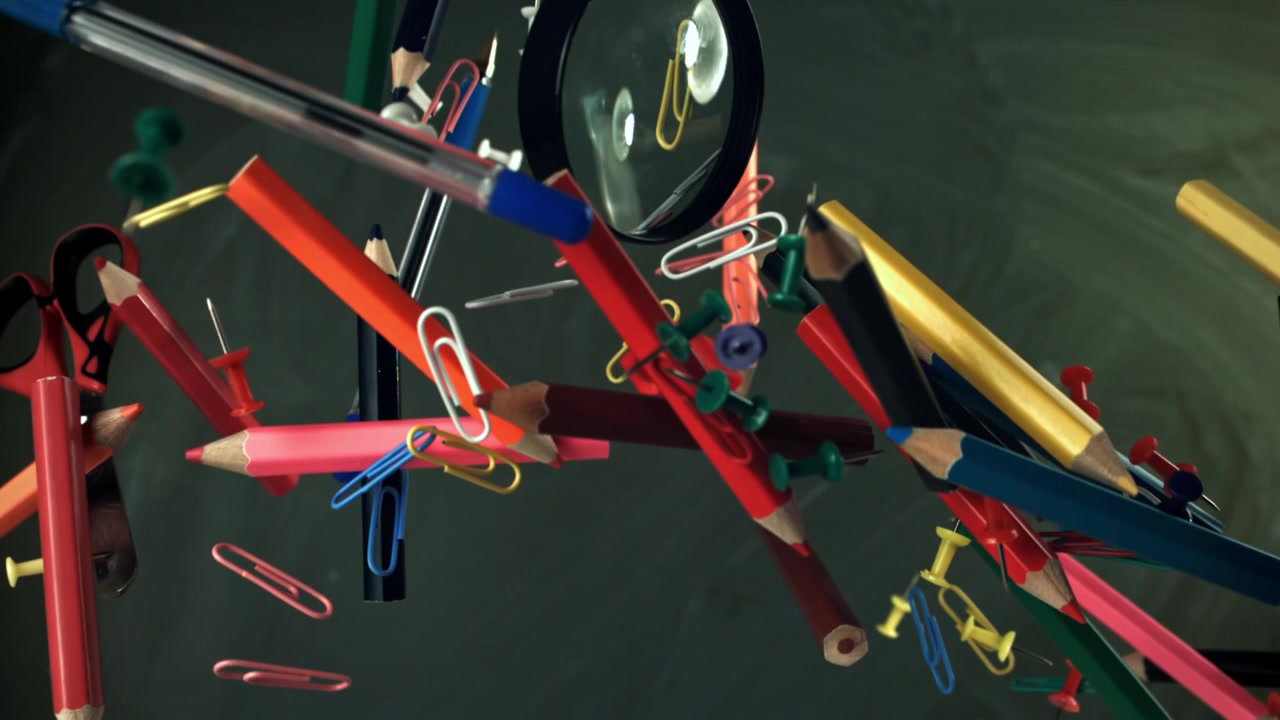 Colorful School and Office Supplies Floating in Slow Motion Against a Blackboard