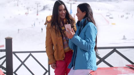 two smiling young women checking a phone