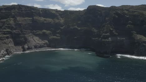 Breathtaking-aerial-view-of-Ponta-da-Ferraria-cliffs-and-ocean-waves-on-a-sunny-day