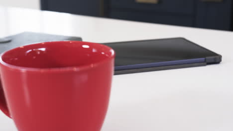 red mug on kitchen counter with tablet, creating cozy holiday atmosphere
