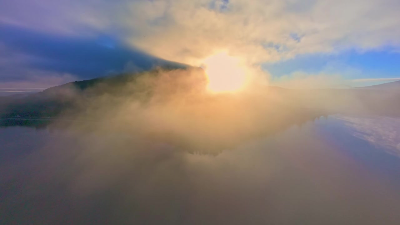 Luce dorata del sole che filtra attraverso la nebbia su un lago di montagna