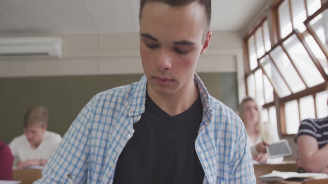 niño caucásico escribiendo en la clase de secundaria