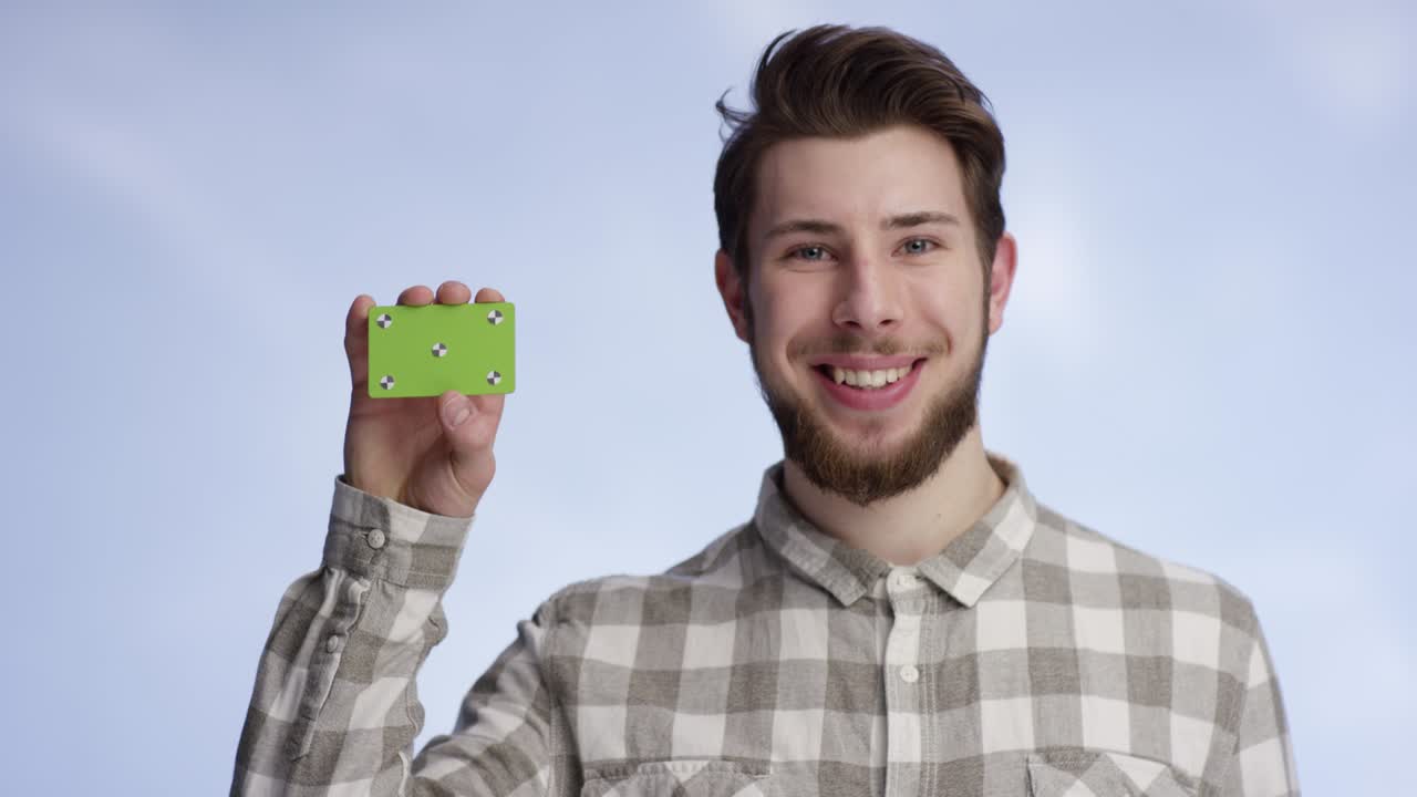 joven y atractivo levantando su tarjeta de negocio en la cámara al lado de su cara