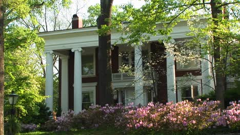 A-Mediumshot-Of-An-Old-But-Well-Kept-Country-Home-Surrounded-By-Trees-And-Bushes