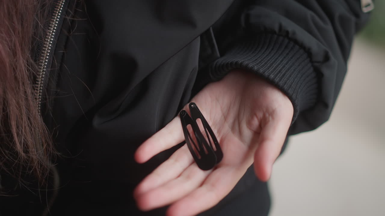 Accessorio per capelli sotto la pioggia. Donna che stringe un elastico per capelli sotto la pioggia. Scatto dettagliato di una donna che afferra un elastico per capelli durante un temporale. Mano femminile che stringe un accessorio per capelli tra pioggia battente e tempo tempestoso.