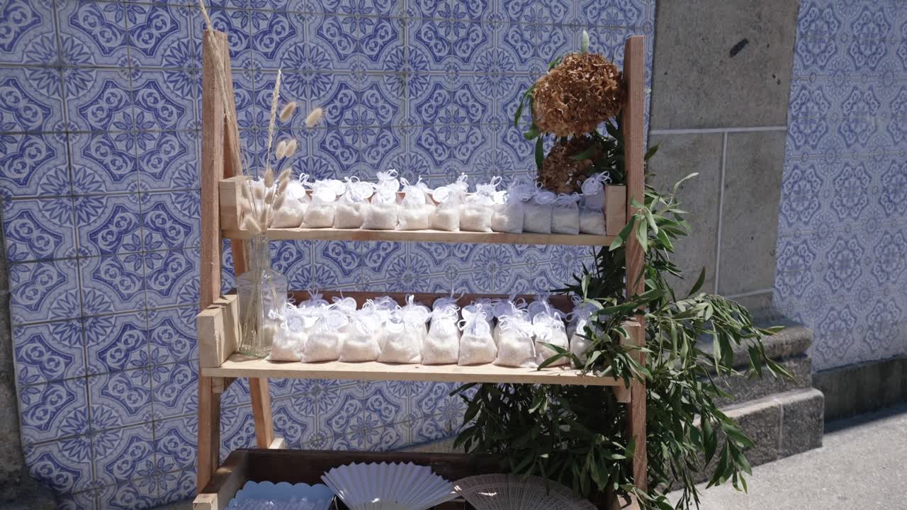 Bomboniere in sacchetti di organza su scaffali di legno con sfondo di azulejos blu