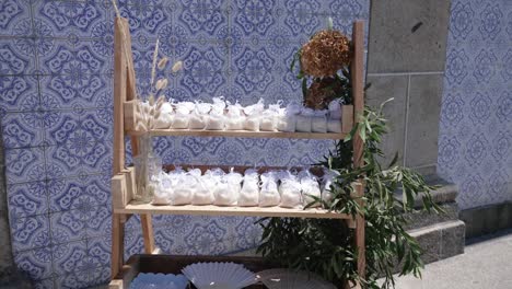 wedding favors in organza bags on wooden shelves with blue azulejo backdrop