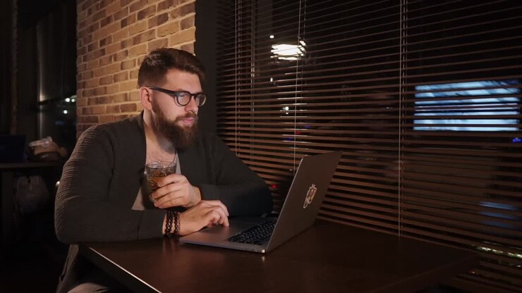 Man working on a laptop in a cafe at night