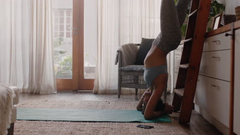 healthy woman exercising at home practicing hand stand in living room enjoying morning fitness workout