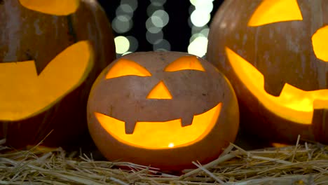 glowing halloween jack-o'-lanterns on straw