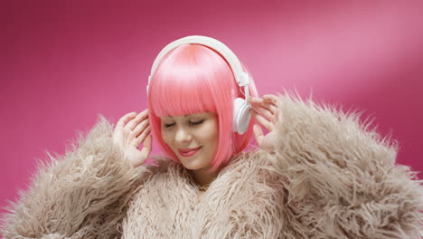 close up of attractive woman wearing a pink wig and headphones and dancing joyfully 2