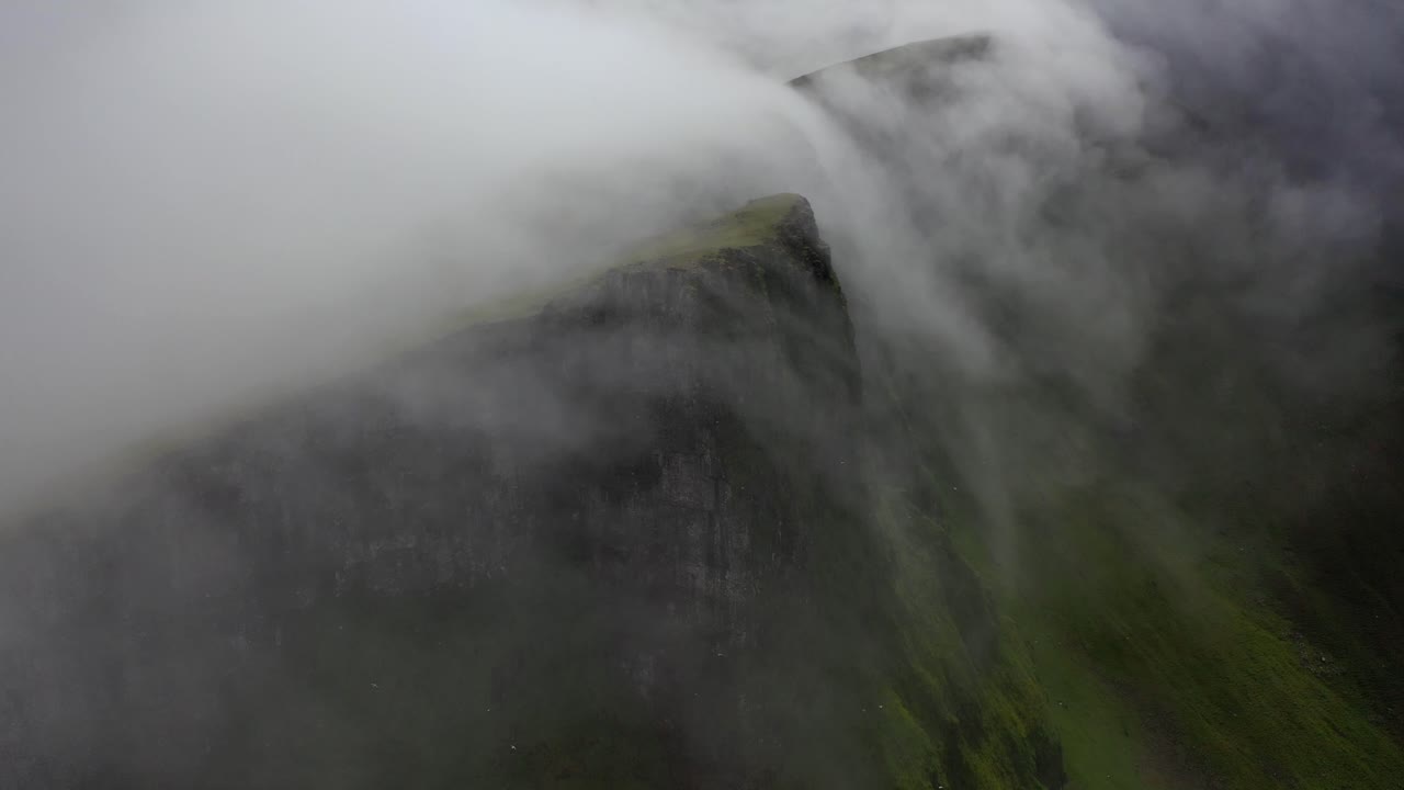 Clouds rolling over mountain peaks in atmospheric natural landscape, aerial view