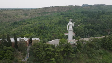 arc aerial shot of the kartlis deda statue and a beautiful tbilisi landscape