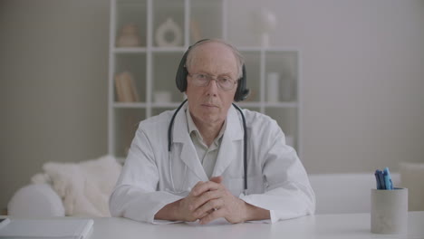Un-Terapeuta-Anciano-Escucha-Al-Paciente-Durante-Una-Consulta-En-Línea-Asintiendo-Con-La-Cabeza,-Retrato-Del-Médico