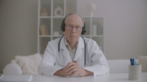 elderly male therapist is listening patient during online consultation nodding head portrait of physician