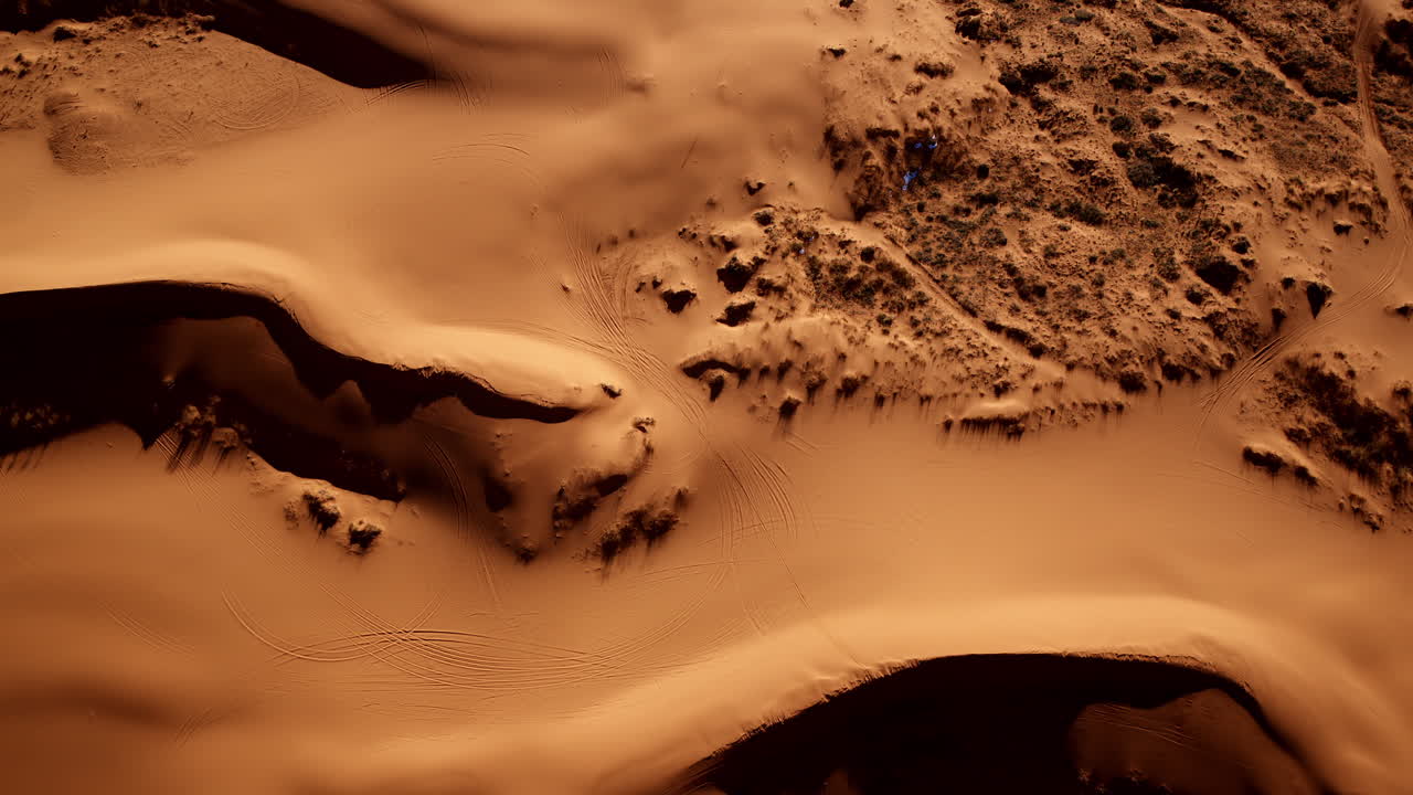 A vertical aerial view of pink sand dunes reveals a colorful and abstract terrain in southern Utah.