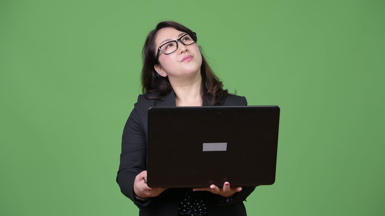 una hermosa mujer de negocios asiática madura usando una computadora portátil contra un fondo verde