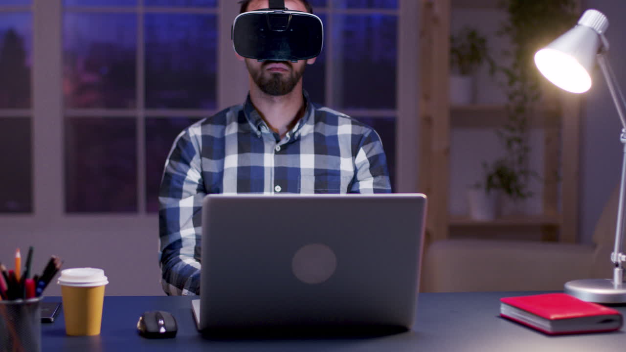 Man using VR headset at desk with laptop