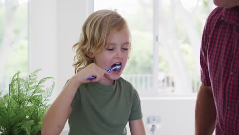 abuelo caucásico ayudando a su nieto a cepillarse los dientes en casa