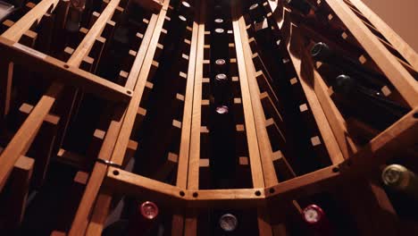 detailed moody shot of a wood wine rack in a luxury home filled with wine bottles