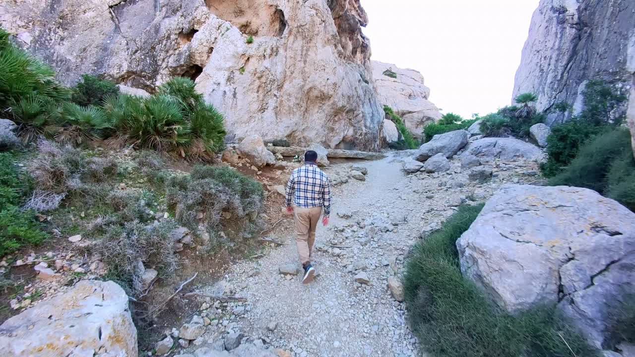 Man Hiking Through Rocky Canyon Trail in Cala Bóquer, Mallorca