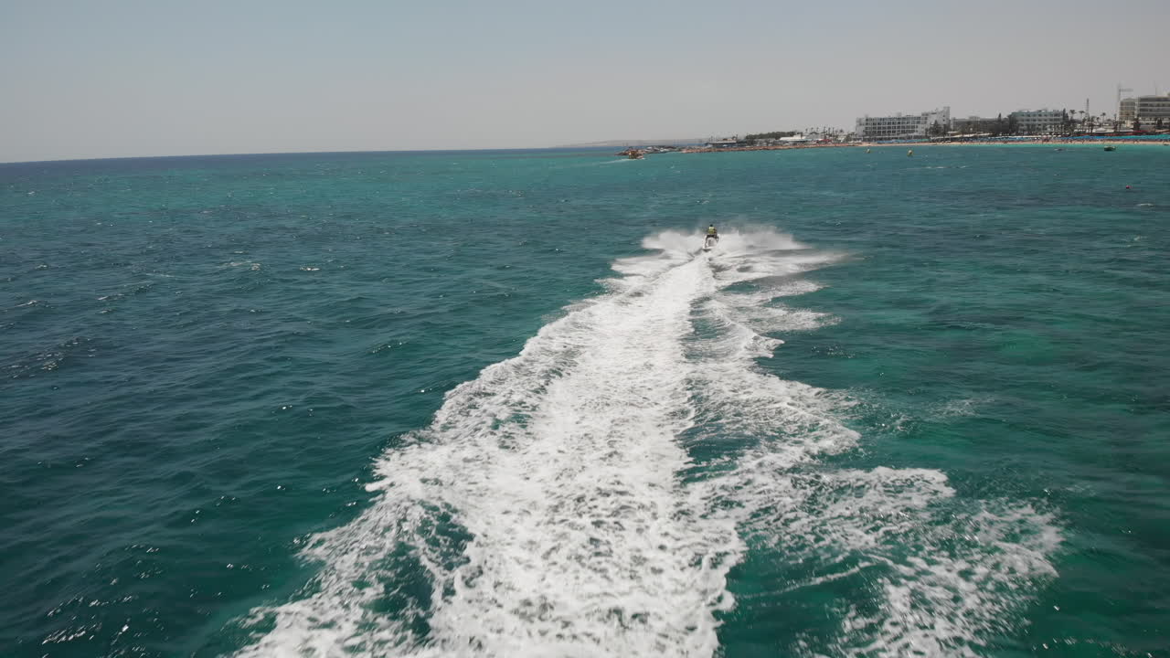 Bright sun shines on a beautiful sea as jetskis glide over the waves. People enjoy water activities in a lively coastal area filled with excitement