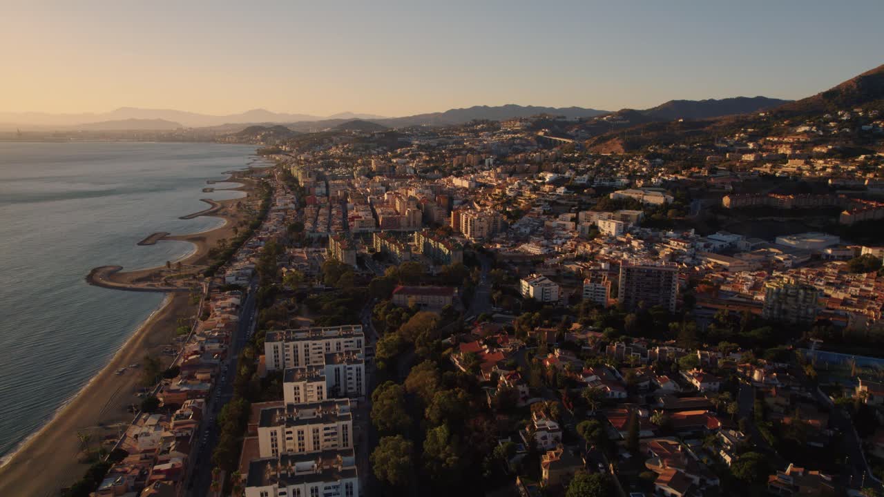 un dron aéreo en movimiento hacia adelante disparó sobre la playa de el candado en málaga españa con hermosa luz del sol en la costa y casas de playa