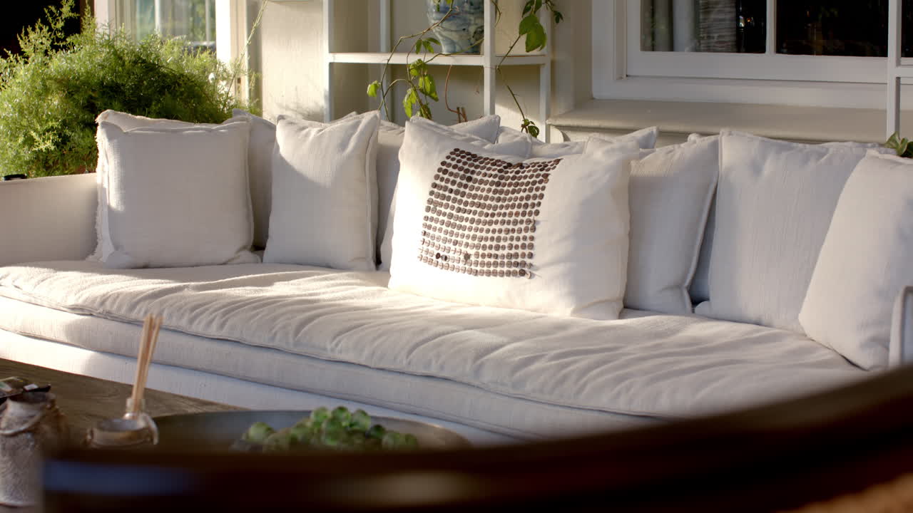 Large white sofa with many cushions, resting on sunny patio