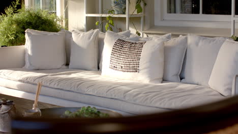 large white sofa with many cushions, resting on sunny patio