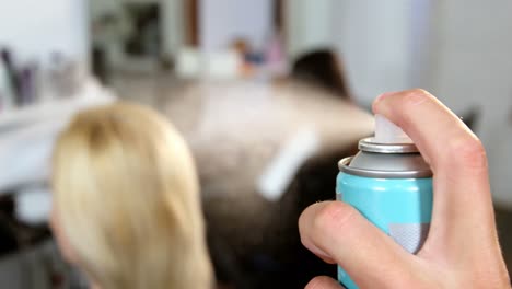 male hairdresser spraying hair spray on womans hair