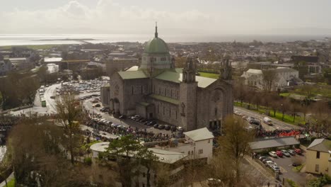 Luftparallaxe-Der-Kathedrale-Von-Galway,-Während-Familien-Zusammenkommen,-Um-Die-Parade-In-Irland-Anzusehen