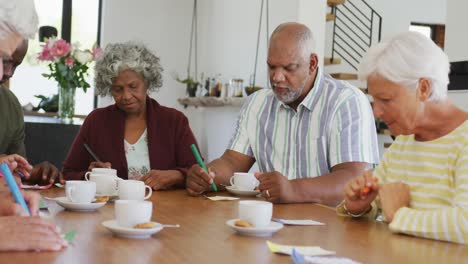 Happy-senior-diverse-people-drinking-tea-and-playing-bingo-at-retirement-home