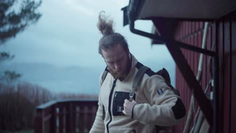 caucasian backpacker leaving home on countryside cottage with overcast sky