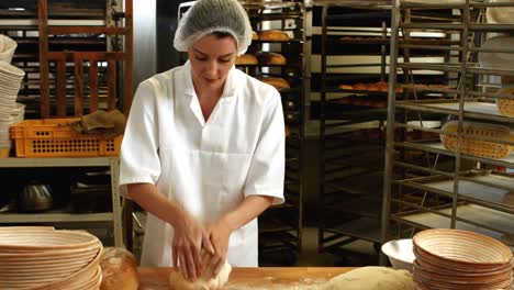 female baker kneading a dough