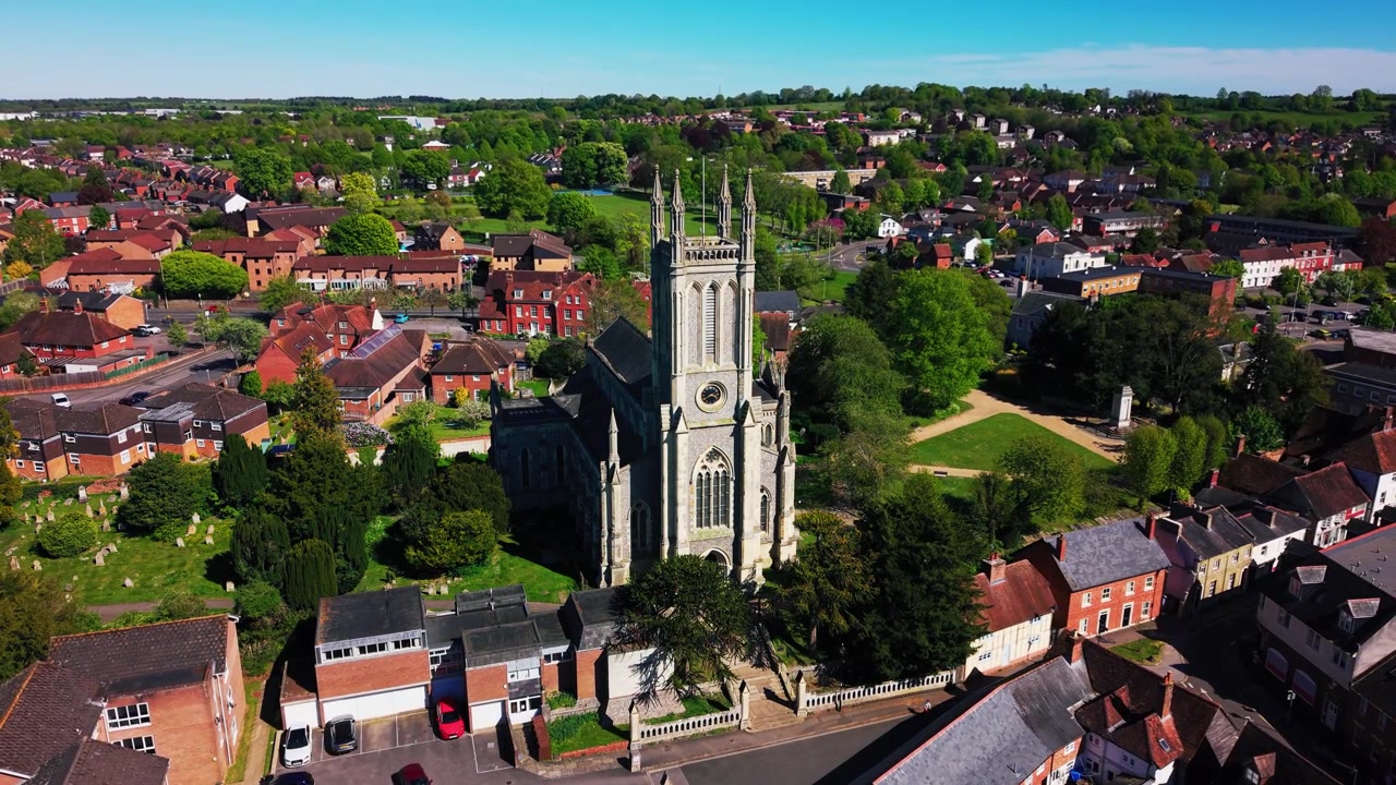 Luchtopnamen met drone van St Mary's Kerk in Andover, met de historische kerktoren, het kerkhof, omliggende straten, daken, bomen en het stadslandschap op een zonnige dag. Nuttig voor Brits erfgoed