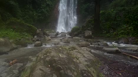 Aerial-backwards-shot-of-Gitgit-Waterfall-with-rocky-stream-in-jungle-of-Bali