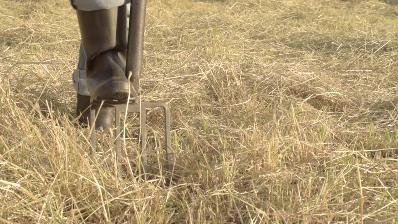 granjero cavando en el campo de heno con tenedor