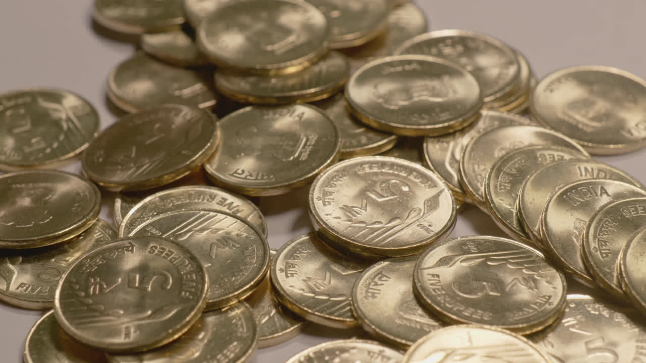 indian currency golden 5 rupee coins scattered on the table , 4k ,close up, orbit shot