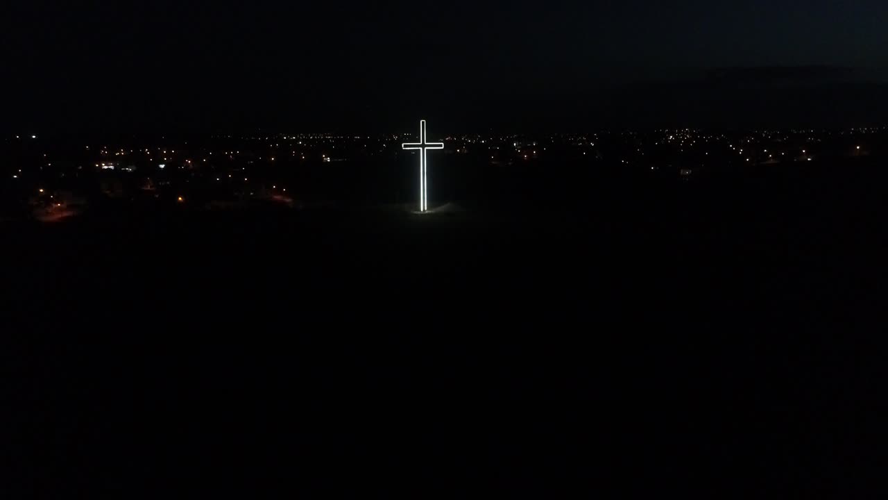 밤에 니코시아 언덕 꼭대기에 빛나는 십자가에 접근하는 공중 드론 샷