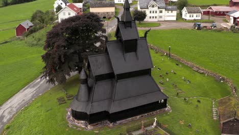 hopperstad stavkyrkje, black wooden stave christian church and village in norway aerial view, ancient norwegian religious monument from 12th century, drone shot