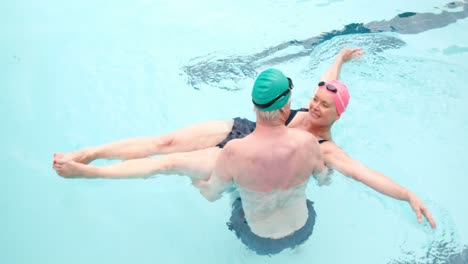 älterer mann trägt eine frau im schwimmbad