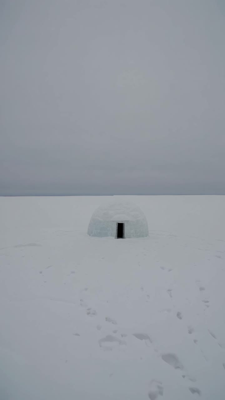 A minimalist video concept featuring an igloo on a vast snowy landscape