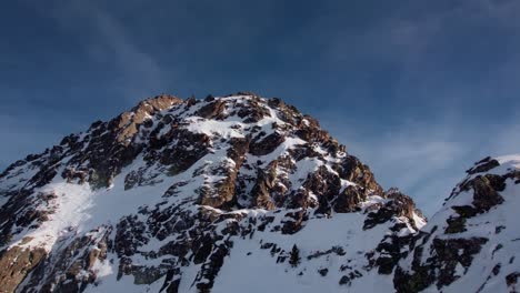 flying towards rocky mountain peak covered in snow, close up