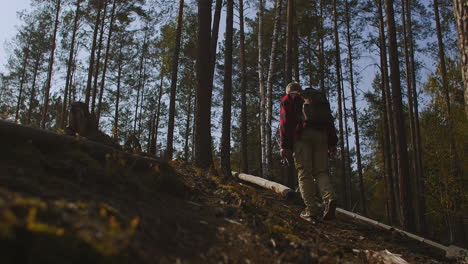 middle-aged man is trekking alone in forest carrying backpack and fishing rod hiking and backpacking