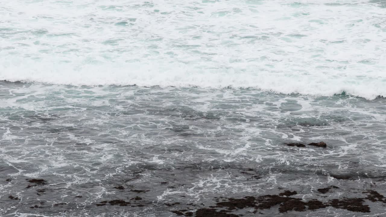Dynamic waves crash against the rocky shore of Great Ocean Road, Australia, captured in natural lighting with a steady camera