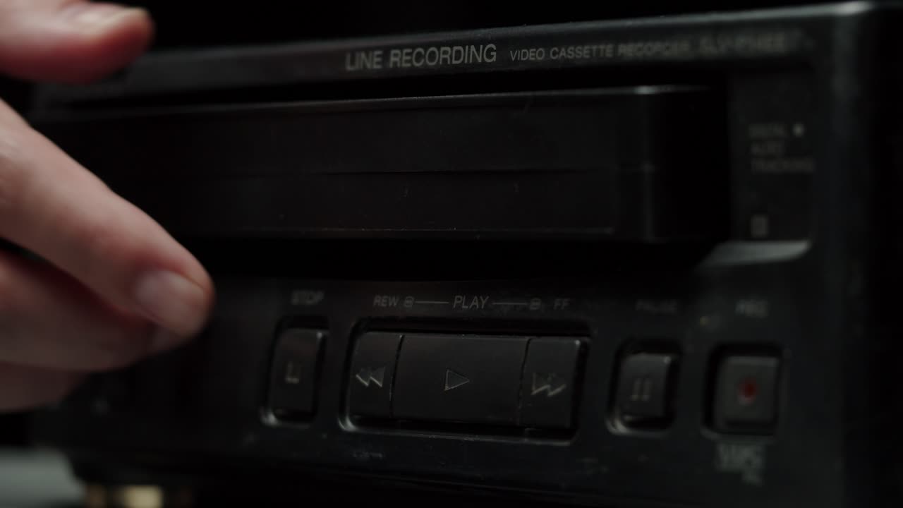 Hånd indsætter og udstøder VHS-bånd fra gammel VCR-afspiller