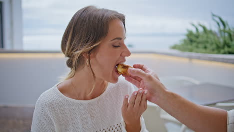 smiling lady relaxing cafeteria closeup. unrecognizable boyfriend feeding woman