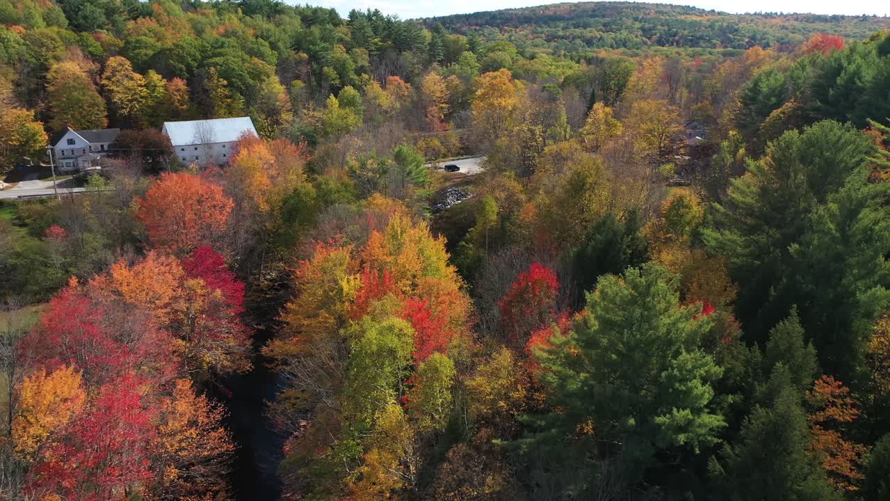 vista aérea de la vívida hoja del bosque otoñal, el arroyo y las casas de campo, el colorido paisaje de cuento de hadas de maine usa, tiro con drones