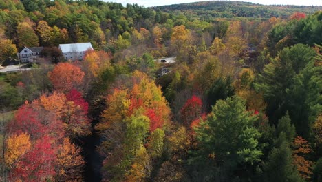 Aerial-View-of-Vivid-Autumn-Forest-Leaf,-Creek-and-Countryside-Houses,-Maine-USA-Colorful-Fairytale-Landscape,-Drone-Shot