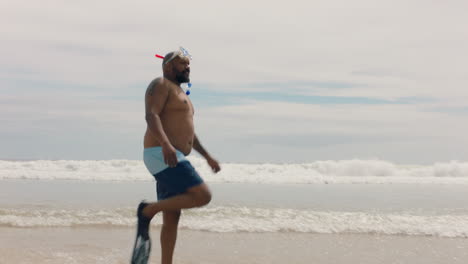 hombre afroamericano divertido caminando por la playa con aletas preparándose para nadar disfrutando del verano junto al mar 4k